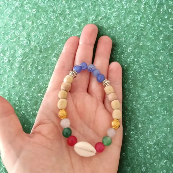 Pulseira de Contas Coloridas e Búzio - Sabedoria e Proteção de Bali: Traga a beleza serena e a sabedoria ancestral da Ilha dos Deuses, Bali (Indonésia), diretamente para o seu pulso. Esta pulseira esotérica artesanal é um poderoso amuleto de proteção e vitalidade, cuidadosamente feita à mão por mestres artesãos balineses.  Energias e Significado Espiritual: As vibrantes contas coloridas não são apenas decorativas; elas representam a energia dos diferentes Chakras, promovendo o equilíbrio energético e infundindo o seu dia com alegria, positivismo e vitalidade. O ponto focal é o búzio natural, um símbolo místico profundamente ligado à espiritualidade e ao mar: Poder Feminino: Representa a Deusa, a beleza natural e a fertilidade, fortalecendo a energia feminina (Yin). Conhecimento Antigo: Simboliza a sabedoria e o conhecimento ancestral, guiando a jornada interior. Proteção Marítima: Atua como um talismã de proteção, promovendo a fluidez e a consciência plena. Uma Joia Espiritual Essencial: Com um design intemporal e ajuste perfeito, esta pulseira unissexo é ideal para qualquer pessoa que procure um acessório esotérico que vá além da estética. É um lembrete constante da sua força interior e da busca por uma vida mais consciente e espiritualmente conectada.Detalhes do Produto: Origem: Bali, Indonésia (Artesanato Autêntico) Significado: Equilíbrio de Chakras, Proteção Espiritual, Sabedoria e Vitalidade. Uso: Joia Espiritual Unissexo (Homens e Mulheres) Vantagem: Leve e ajustável, garantindo o máximo conforto e adaptabilidade. Leve consigo a magia de Bali e a poderosa energia da sabedoria e da beleza natural.