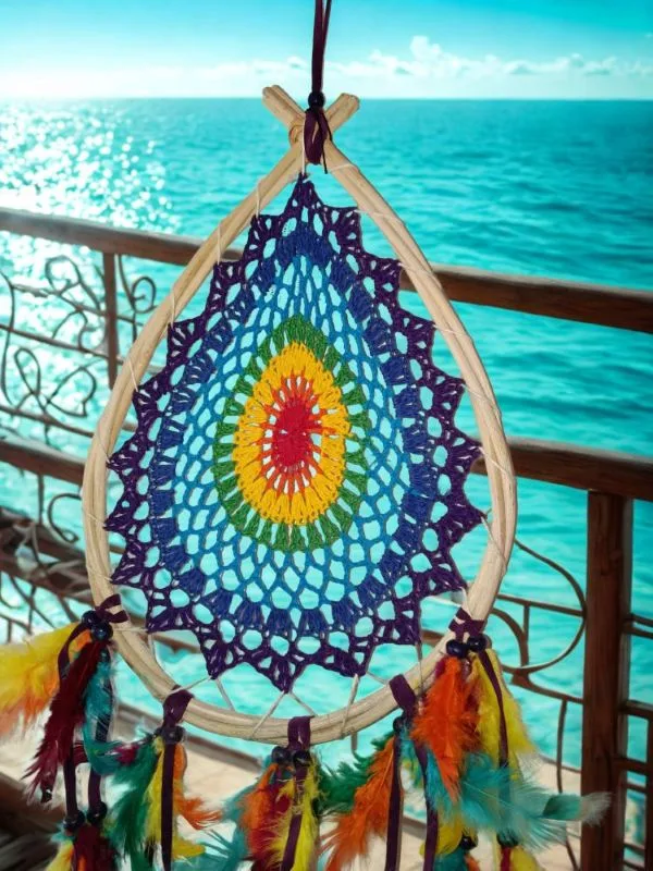Caça-Sonhos 7 Chakras Artesanal - Equilíbrio Energético e Proteção de Bali​: Transforme a energia do seu espaço e garanta um sono reparador e protegido com este exclusivo Caça-Sonhos 7 Chakras. Uma peça que transcende a decoração: é um poderoso portal de cura energética, alinhamento e proteção espiritual.✨ Características Místicas e Artesanais​: Artesanato Esotérico de Bali: Cuidadosamente feito à mão por artesãos locais na Ilha dos Deuses, Bali (Indonésia), capturando a essência da espiritualidade insular e da arte balinesa.Teia de Proteção Energética: O intrincado padrão de renda no centro funciona como uma teia mística onde os pesadelos e as energias densas são presos, permitindo que apenas os sonhos positivos e a inspiração passem.Alinhamento dos 7 Chakras: O elemento central apresenta as 7 cores dos chakras principais (Raiz, Sacral, Plexo Solar, Cardíaco, Laríngeo, Terceiro Olho e Coroa). Esta incorporação confere-lhe um propósito ativo de cura e harmonização, atuando no seu campo energético enquanto dorme ou medita.Vibração e Leveza: Composto por múltiplas camadas de penas multicoloridas, este amuleto de proteção cria um efeito visual deslumbrante que simboliza a leveza da alma e a liberdade espiritual.🧘 O Poder Esotérico do Caça-Sonhos (Dreamcatcher) é um amuleto tradicional essencial para quem busca a proteção noturna:​ Filtro de Sonhos: A teia apanha as energias negativas da noite, que são purificadas pela luz da manhã, garantindo que apenas as visões positivas e inspiradoras cheguem até si, escorregando suavemente pelas penas.​ Cura e Equilíbrio Energético: Além da proteção, este Dreamcatcher com as cores dos Chakras promove ativamente o alinhamento dos pontos de energia, fomentando a saúde física, emocional e espiritual.​ Decoração Consciente: Perfeito para ser o ponto focal no seu quarto, espaço de meditação, altar ou qualquer canto que necessite de uma elevação de energia e um toque de vibração positiva.Traga a magia de Bali e a sabedoria dos Chakras para a sua vida. Invista em noites de sono reparadoras e na harmonia energética do seu lar!
