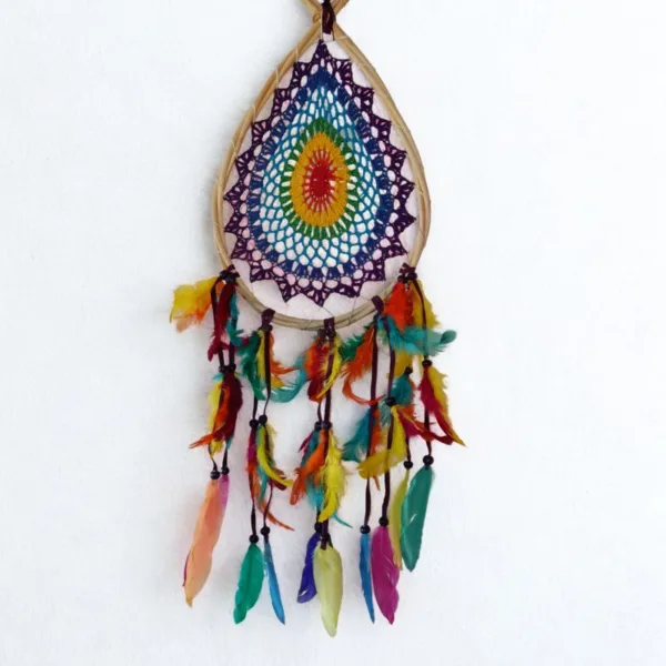 Caça-Sonhos 7 Chakras Artesanal - Equilíbrio Energético e Proteção de Bali​: Transforme a energia do seu espaço e garanta um sono reparador e protegido com este exclusivo Caça-Sonhos 7 Chakras. Uma peça que transcende a decoração: é um poderoso portal de cura energética, alinhamento e proteção espiritual.✨ Características Místicas e Artesanais​: Artesanato Esotérico de Bali: Cuidadosamente feito à mão por artesãos locais na Ilha dos Deuses, Bali (Indonésia), capturando a essência da espiritualidade insular e da arte balinesa.Teia de Proteção Energética: O intrincado padrão de renda no centro funciona como uma teia mística onde os pesadelos e as energias densas são presos, permitindo que apenas os sonhos positivos e a inspiração passem.Alinhamento dos 7 Chakras: O elemento central apresenta as 7 cores dos chakras principais (Raiz, Sacral, Plexo Solar, Cardíaco, Laríngeo, Terceiro Olho e Coroa). Esta incorporação confere-lhe um propósito ativo de cura e harmonização, atuando no seu campo energético enquanto dorme ou medita.Vibração e Leveza: Composto por múltiplas camadas de penas multicoloridas, este amuleto de proteção cria um efeito visual deslumbrante que simboliza a leveza da alma e a liberdade espiritual.🧘 O Poder Esotérico do Caça-Sonhos (Dreamcatcher) é um amuleto tradicional essencial para quem busca a proteção noturna:​ Filtro de Sonhos: A teia apanha as energias negativas da noite, que são purificadas pela luz da manhã, garantindo que apenas as visões positivas e inspiradoras cheguem até si, escorregando suavemente pelas penas.​ Cura e Equilíbrio Energético: Além da proteção, este Dreamcatcher com as cores dos Chakras promove ativamente o alinhamento dos pontos de energia, fomentando a saúde física, emocional e espiritual.​ Decoração Consciente: Perfeito para ser o ponto focal no seu quarto, espaço de meditação, altar ou qualquer canto que necessite de uma elevação de energia e um toque de vibração positiva.Traga a magia de Bali e a sabedoria dos Chakras para a sua vida. Invista em noites de sono reparadoras e na harmonia energética do seu lar!