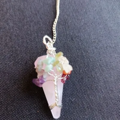 Pêndulo de Quartzo Rosa e 7 Chakras - Radiestesia, Amor e Equilíbrio Energético Eleve sua prática radiestésica e harmonize seu campo vibracional com este deslumbrante Pêndulo de Cura, uma ferramenta esotérica poderosa que combina a energia do Amor Incondicional do Quartzo Rosa com o alinhamento completo dos seus centros energéticos. 💎 A Força do Quartzo Rosa para Radiestesia Este pêndulo é meticulosamente esculpido em Quartzo Rosa natural, a pedra do amor, paz e cura emocional. Propriedades de Cura: Atua diretamente no Chakra Cardíaco, acalmando o sistema nervoso e promovendo a autoestima, a aceitação e a abertura para receber e dar amor. Vibração Ideal: Sua energia suave e compassiva é perfeita para radiestesistas que buscam sensibilidade e empatia em seus trabalhos. Aplicações Terapêuticas: Ideal para detecção de padrões energéticos em relacionamentos, localização de bloqueios emocionais e medição da vibração de ambientes para promover harmonia e bem-estar. 🌈 O Toque dos 7 Chakras: Multiplicador de Energia O pêndulo é ricamente adornado na sua corrente com pequenas pedras naturais representando os sete principais chakras. Esta adição é fundamental para potencializar sua prática de cura energética: Equilíbrio e Neutralidade: Cada pedra (representando os chakras Raiz ao Coroa) atua como um multiplicador de energia, garantindo que o instrumento de radiestesia opere a partir de um estado de equilíbrio vibracional e neutralidade completa. Foco e Precisão: Ajuda o operador a manter a conexão intuitiva com todos os seus centros de energia durante a consulta, resultando em respostas intuitivas mais claras e precisas. Adquira o Seu! Este pêndulo divinatório é um instrumento de trabalho que une a beleza da natureza à potência energética necessária para suas investigações. Perfeito para quem busca respostas intuitivas ancoradas no amor e na harmonia. Leve o equilíbrio dos chakras e a suavidade do Quartzo Rosa para a sua mesa de trabalho esotérica!