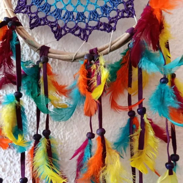 Caça-Sonhos 7 Chakras Artesanal - Equilíbrio Energético e Proteção de Bali​: Transforme a energia do seu espaço e garanta um sono reparador e protegido com este exclusivo Caça-Sonhos 7 Chakras. Uma peça que transcende a decoração: é um poderoso portal de cura energética, alinhamento e proteção espiritual.✨ Características Místicas e Artesanais​: Artesanato Esotérico de Bali: Cuidadosamente feito à mão por artesãos locais na Ilha dos Deuses, Bali (Indonésia), capturando a essência da espiritualidade insular e da arte balinesa.Teia de Proteção Energética: O intrincado padrão de renda no centro funciona como uma teia mística onde os pesadelos e as energias densas são presos, permitindo que apenas os sonhos positivos e a inspiração passem.Alinhamento dos 7 Chakras: O elemento central apresenta as 7 cores dos chakras principais (Raiz, Sacral, Plexo Solar, Cardíaco, Laríngeo, Terceiro Olho e Coroa). Esta incorporação confere-lhe um propósito ativo de cura e harmonização, atuando no seu campo energético enquanto dorme ou medita.Vibração e Leveza: Composto por múltiplas camadas de penas multicoloridas, este amuleto de proteção cria um efeito visual deslumbrante que simboliza a leveza da alma e a liberdade espiritual.🧘 O Poder Esotérico do Caça-Sonhos (Dreamcatcher) é um amuleto tradicional essencial para quem busca a proteção noturna:​ Filtro de Sonhos: A teia apanha as energias negativas da noite, que são purificadas pela luz da manhã, garantindo que apenas as visões positivas e inspiradoras cheguem até si, escorregando suavemente pelas penas.​ Cura e Equilíbrio Energético: Além da proteção, este Dreamcatcher com as cores dos Chakras promove ativamente o alinhamento dos pontos de energia, fomentando a saúde física, emocional e espiritual.​ Decoração Consciente: Perfeito para ser o ponto focal no seu quarto, espaço de meditação, altar ou qualquer canto que necessite de uma elevação de energia e um toque de vibração positiva.Traga a magia de Bali e a sabedoria dos Chakras para a sua vida. Invista em noites de sono reparadoras e na harmonia energética do seu lar!