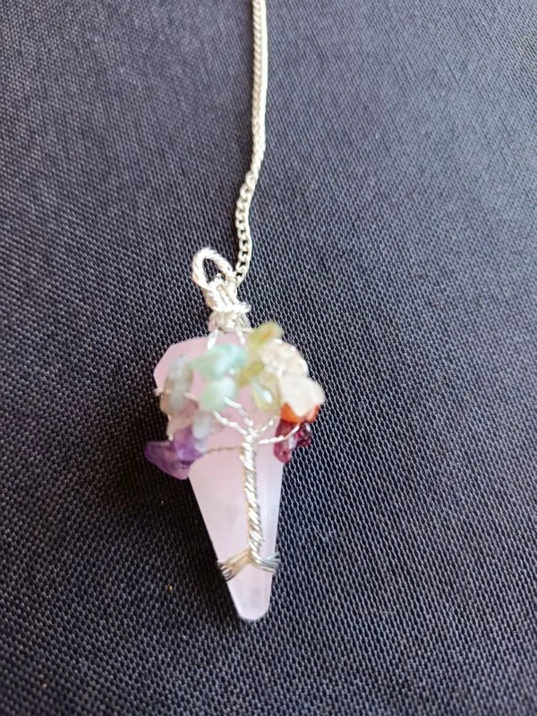 Pêndulo de Quartzo Rosa e 7 Chakras - Radiestesia, Amor e Equilíbrio Energético Eleve sua prática radiestésica e harmonize seu campo vibracional com este deslumbrante Pêndulo de Cura, uma ferramenta esotérica poderosa que combina a energia do Amor Incondicional do Quartzo Rosa com o alinhamento completo dos seus centros energéticos. 💎 A Força do Quartzo Rosa para Radiestesia Este pêndulo é meticulosamente esculpido em Quartzo Rosa natural, a pedra do amor, paz e cura emocional. Propriedades de Cura: Atua diretamente no Chakra Cardíaco, acalmando o sistema nervoso e promovendo a autoestima, a aceitação e a abertura para receber e dar amor. Vibração Ideal: Sua energia suave e compassiva é perfeita para radiestesistas que buscam sensibilidade e empatia em seus trabalhos. Aplicações Terapêuticas: Ideal para detecção de padrões energéticos em relacionamentos, localização de bloqueios emocionais e medição da vibração de ambientes para promover harmonia e bem-estar. 🌈 O Toque dos 7 Chakras: Multiplicador de Energia O pêndulo é ricamente adornado na sua corrente com pequenas pedras naturais representando os sete principais chakras. Esta adição é fundamental para potencializar sua prática de cura energética: Equilíbrio e Neutralidade: Cada pedra (representando os chakras Raiz ao Coroa) atua como um multiplicador de energia, garantindo que o instrumento de radiestesia opere a partir de um estado de equilíbrio vibracional e neutralidade completa. Foco e Precisão: Ajuda o operador a manter a conexão intuitiva com todos os seus centros de energia durante a consulta, resultando em respostas intuitivas mais claras e precisas. Adquira o Seu! Este pêndulo divinatório é um instrumento de trabalho que une a beleza da natureza à potência energética necessária para suas investigações. Perfeito para quem busca respostas intuitivas ancoradas no amor e na harmonia. Leve o equilíbrio dos chakras e a suavidade do Quartzo Rosa para a sua mesa de trabalho esotérica!