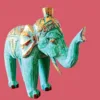 Escultura Elefante Madeira Bali Artesanal | Dourado e Turquesa | Decoração Asiática Étnica Adicione um toque de sabedoria e exotismo à sua decoração com esta manífica escultura de elefante em madeira. Cada peça é esculpida à mão por mestres artesãos na ilha paradisíaca de Bali, na Indonésia, garantindo um artigo único e cheio de carácter! Características Principais: Artesanato Autêntico de Bali: Esta escultura é o resultado de técnicas tradicionais de entalhe em madeira, passadas de geração em geração. Design Exclusivo: O acabamento em tons vibrantes do dourado e turquesa conferem um charme especial, combinando a riqueza cultural com um toque moderno.Simbolismo de Sorte e Sabedoria: Na cultura asiática, o elefante é um animal sagrado, símbolo de sorte, prosperidade e sabedoria. Material Natural: Feita a partir de madeira sustentável (madeira de Albésia, leve e durável), esta elegante peça é ecológica e robusta. Decoração Étnica e Zen: Perfeita para criar um ambiente Zen, étnico ou para adicionar um ponto focal de cor em qualquer divisão da sua casa, escritório ou espaço de meditação. Ideal Para:Amantes de artesanato e decoração asiática ou étnica. Quem procura um amuleto de boa sorte e prosperidade para o seu lar. Prendas únicas com significado!Nota: Por se tratar de um produto artesanal, pequenas variações nas cores e nos detalhes podem ocorrer, o que torna a sua peça verdadeiramente exclusiva. e com significado!Nota: Por se tratar de um produto artesanal, pequenas variações nas cores e nos detalhes podem ocorrer, o que torna a sua peça verdadeiramente exclusiva.