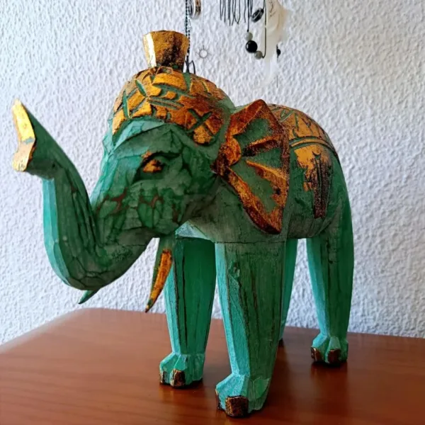Escultura Elefante Madeira Bali Artesanal | Dourado e Turquesa | Decoração Asiática Étnica Adicione um toque de sabedoria e exotismo à sua decoração com esta manífica escultura de elefante em madeira. Cada peça é esculpida à mão por mestres artesãos na ilha paradisíaca de Bali, na Indonésia, garantindo um artigo único e cheio de carácter! Características Principais: Artesanato Autêntico de Bali: Esta escultura é o resultado de técnicas tradicionais de entalhe em madeira, passadas de geração em geração. Design Exclusivo: O acabamento em tons vibrantes do dourado e turquesa conferem um charme especial, combinando a riqueza cultural com um toque moderno.Simbolismo de Sorte e Sabedoria: Na cultura asiática, o elefante é um animal sagrado, símbolo de sorte, prosperidade e sabedoria. Material Natural: Feita a partir de madeira sustentável (madeira de Albésia, leve e durável), esta elegante peça é ecológica e robusta. Decoração Étnica e Zen: Perfeita para criar um ambiente Zen, étnico ou para adicionar um ponto focal de cor em qualquer divisão da sua casa, escritório ou espaço de meditação. Ideal Para:Amantes de artesanato e decoração asiática ou étnica. Quem procura um amuleto de boa sorte e prosperidade para o seu lar. Prendas únicas com significado!Nota: Por se tratar de um produto artesanal, pequenas variações nas cores e nos detalhes podem ocorrer, o que torna a sua peça verdadeiramente exclusiva. e com significado!Nota: Por se tratar de um produto artesanal, pequenas variações nas cores e nos detalhes podem ocorrer, o que torna a sua peça verdadeiramente exclusiva.