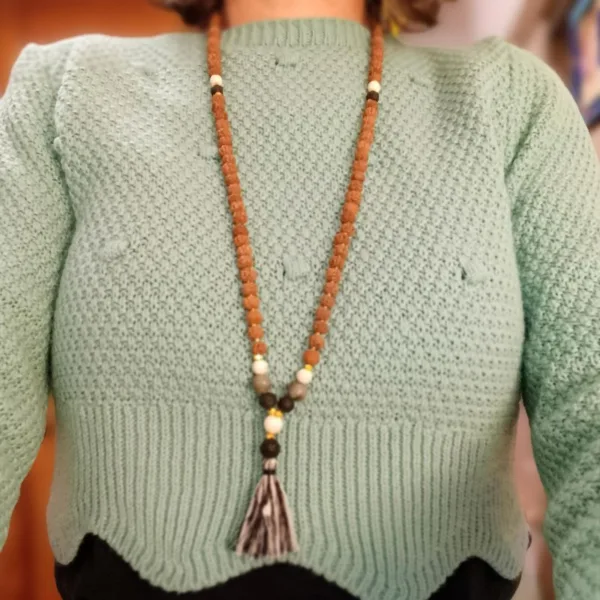 Colar Mala de Bali Artesanal  | Confiança | Feito à Mão Apresentamos um autêntico Colar Mala de Bali, uma peça de artesanato que transcende a simples beleza. Este colar, tradicionalmente conhecido como Japa Mala, é mais do que um acessório étnico; é um poderoso amuleto de confiança e uma ferramenta ancestral para qualquer prática de meditação, yoga na entoação das Mantras e mindfulness. Cada Mala contém as místicas 108 contas, um número que simboliza a totalidade da vida e a conexão entre o corpo, a mente e o espírito. O Mala da Confiança representa os cinco elementos clássicos: Terra (Prithvi/Bhumi), com estabilidade e conexão com as raízes. Água (Jala/Varuna) com fluidez, emoções e intuição. Fogo (Agni/Tejas) – com energia, transformação e força interior. Ar (Vayu/Pavan) com movimento, liberdade e clareza mental. Éter (Akasha) com espiritualidade, expansão e conexão universaAcredita-se que a harmonização destas energias contribui para um equilíbrio físico, mental e espiritual, promovendo confiança e bem-estar. Significado e Propósito (Confiança): O uso de um colar Mala ajuda a focar a mente e a intenção. Ao deslizar os dedos por cada uma das [Normalmente 108] contas, pode recitar um mantra ou afirmação. Este colar específico foi concebido para fortalecer a confiança e a determinação, servindo como um lembrete físico do seu poder interior e resiliência. Especificações Principais: Autenticidade Balinesa: Produto genuíno de artesanato da Indonésia, refletindo a tradição espiritual local. Feito à Mão: Cada nó e cada montagem são realizados manualmente com precisão e cuidado, garantindo durabilidade e uma textura tátil agradável. Design Boho-Chic: Combina a funcionalidade espiritual com um estilo boho e zen, perfeito para uso diário como um colar longo ou enrolado no pulso como pulseira. Amuletos e Talismãs: Um acessório carregado de significado, ideal para quem valoriza joalharia com propósito e acessórios artesanais.Ideal Para: Praticantes de meditação e yoga. Quem procura um acessório simbólico para aumentar a confiança e a clareza mental. Amantes de decoração étnica e estilo natural. Presentes originais e cheias de significado! Detalhes do Produto: Nome do Produto: Colar Mala de Bali - Confiança Origem: Bali, Indonésia Nota: As propriedades metafísicas atribuídas às pedras ou sementes são baseadas em crenças culturais e práticas espirituais. Cada Mala é único, podendo haver ligeiras variações de cor e tamanho.