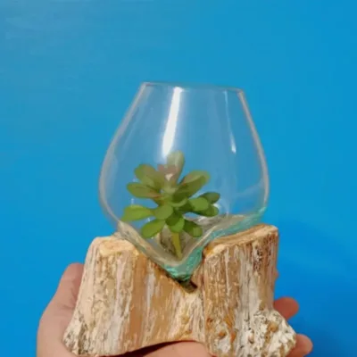 Peça em Vidro Fundido em Madeira, de Bali | Peça Artesanal Média | Decoração Única Preparada/o para ter uma bela peça de artesanato Balinês? Artesanato Genuíno de Bali: Cada artigo é feito à mão por mestres artesãos na Indonésia, garantindo autenticidade e apoio à comunidade local. Design Rústico Chic: A combinação da madeira branca com o vidro transparente oferece um visual Shabby Chic, costeiro ou Zen que ilumina qualquer espaço. Versatilidade Decorativa: De tamanho médio, esta peça é ideal como um centro de mesa elegante, como porta - vela,  um terrário para suculentas ou simplesmente como uma escultura decorativa por si só. Sustentabilidade e Compra Consciente: Utilizamos vidro reciclado e madeira local, numa abordagem ecológica e amiga do ambiente. Ponto Focal de Luz: O vidro incolor capta e reflete a luz, criando um efeito visual deslumbrante em qualquer divisão. Porquê Comprar Esta Peça Única? Esta não é apenas uma peça de decoração, é um convite à calma e uma celebração da beleza natural e imperfeita. É a escolha perfeita para quem procura um presente original e de bom gosto, ou para adicionar um toque de sofisticação artesanal à sua própria casa​, local de trabalho, lar de férias. O stock destas peças é naturalmente limitado devido ao processo de criação manual e exclusivo. Garanta já a sua! Não perca a oportunidade de possuir esta fusão ​l​indíssima de elementos naturais e design costeiro! Adicione esta Peça Exclusiva de Vidro e Madeira à Sua Decoração!  https://lojaom.pt/?post_type=product&p=718&preview=true ​ ​Explore a nossa http://www.lojaom.pt  para mais artigos de decoração étnica, artigos esotéricos e arte balinesa!