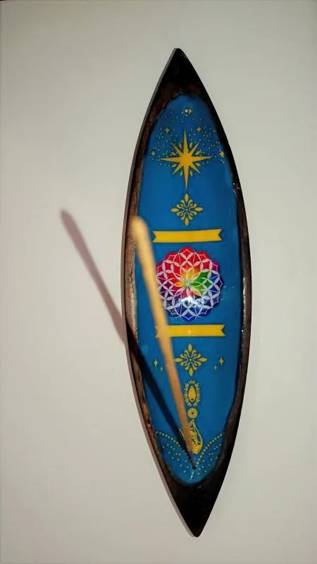 O Equilíbrio Perfeito entre Arte e Espiritualidade: Este não é apenas um lindo porta-incensos, é um objeto de decoração zen desenhado para elevar a vibração do seu altar ou espaço de meditação. O detalhe central da mandala esmaltada não só embeleza o ambiente, como serve de foco visual para práticas de concentração e alinhamento energético. Porquê escolher este Suporte de Incensos de Madeira de Manga? Autenticidade Handmade: Por ser um artigo feito à mão, cada suporte possui veios e detalhes únicos na madeira, garantindo que terá uma peça exclusiva no mundo! Sustentabilidade: A madeira de manga é reconhecida pela sua durabilidade e por ser uma escolha amiga do ambiente no mundo do artesanato esotérico. Design Funcional: O formato longo é ideal para recolher as cinzas das varetas de incenso de forma limpa e segura, protegendo os seus móveis. Pode queimar duas varetas de incensos em simultâneo. Estética Boho-Chic: O acabamento esmaltado vibrante contrasta com o rústico da madeira, adaptando-se perfeitamente a qualquer estilo de decoração mística. Ideal para os seus Rituais de Bem-Estar Seja para uma sessão de Yoga, uma limpeza com Palo Santo ou simplesmente para perfumar a casa, este suporte é o acessório essencial! A simbologia da Mandala no centro ajuda a irradiar harmonia e equilíbrio, tornando as suas práticas de limpeza energética muito mais profundas. Dica Espiritual: Utilize este suporte no seu cantinho de leitura ou trabalho para manter a energia fluida e o foco elevado através da aromaterapia. Especificações: Material: Madeira de Manga de alta qualidade com detalhe esmaltado. Origem: Importado da Índia (Trabalho artesanal). Uso: Compatível com incensos em vareta tradicionais. Não deixe jamais a sua energia estagnar! Traga um pedaço da sabedoria Indiana para o seu lar e sinta a diferença da vibração energética no seu ambiente. Adicionar ao carrinho
