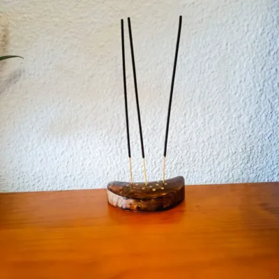 Suporte de Incenso em Madeira Meia-Lua: Constelação de Peixes (Artesanato da Índia)Transforme o seu ritual de defumação numa experiência celestial. O nosso Suporte de Incenso em Madeira em forma de Meia-Lua é mais do que um acessório; é uma peça de arte mística, esculpida à mão por artesãos talentosos na Índia, capturando a essência espiritual do signo de Peixes.A Magia Diferenciadora dos Detalhes: Constelação Incrustada em latãoO grande diferencial deste artesanato reside na sua incrustação metálica detalhada, que desenha com precisão a Constelação de Peixes.Madeira de Manga - Alta Qualidade: Feito em madeira de Manga, durável com acabamento rústico e natural, que traz o elemento "Terra" para o seu altar ou seu espaço de meditação ou de práticas de Autocuidado e AutoAmor!Simbologia Esotérica: A união da Lua (emoções e subconsciente) com a constelação de Peixes (espiritualidade e sonhos) cria um amuleto poderoso para si! Um autêntico artesanato Ativador da sua Transformação Energética!Para quê usar este Suporte de Incensos da lojaom.pt?Se é um nativo de Peixes, ou se deseja invocar as energias de serenidade, sensibilidade e intuição deste signo, este suporte é indispensável. É o artigo ideal para:Rituais de Meditação: Queime o seu incenso favorito enquanto se conecta com as estrelas. Até pode queimar 3 incensos em simultâneo, neste suporte.Decoração Esotérica: Uma peça que se destaca em qualquer prateleira, mesa, num espaço de ioga, meditação e/ou práticas energéticas.Presente com Significado: Surpreenda alguém especial com um  artesanato indiano autêntico que celebra a sua identidade astrológica! O Presente Perfeito para a Temporada de PeixesNão se contente com o comum, cada suporte é único! Traga para o seu lar um pedaço do céu noturno e a tradição milenar da Índia, num artesanato feito segundo tradições ancestrais. Este suporte de incenso é o companheiro perfeito para os nossos Óleos de Fragrância do Zodíaco, criando uma sinergia completa de aroma e simbolismo.Compre o seu suporte meia-lua - signo de Peixes hoje mesmo!