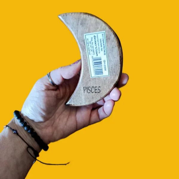 Suporte de Incenso em Madeira Meia-Lua: Constelação de Peixes (Artesanato da Índia)Transforme o seu ritual de defumação numa experiência celestial. O nosso Suporte de Incenso em Madeira em forma de Meia-Lua é mais do que um acessório; é uma peça de arte mística, esculpida à mão por artesãos talentosos na Índia, capturando a essência espiritual do signo de Peixes.A Magia Diferenciadora dos Detalhes: Constelação Incrustada em latãoO grande diferencial deste artesanato reside na sua incrustação metálica detalhada, que desenha com precisão a Constelação de Peixes.Madeira de Manga - Alta Qualidade: Feito em madeira de Manga, durável com acabamento rústico e natural, que traz o elemento "Terra" para o seu altar ou seu espaço de meditação ou de práticas de Autocuidado e AutoAmor!Simbologia Esotérica: A união da Lua (emoções e subconsciente) com a constelação de Peixes (espiritualidade e sonhos) cria um amuleto poderoso para si! Um autêntico artesanato Ativador da sua Transformação Energética!Para quê usar este Suporte de Incensos da lojaom.pt?Se é um nativo de Peixes, ou se deseja invocar as energias de serenidade, sensibilidade e intuição deste signo, este suporte é indispensável. É o artigo ideal para:Rituais de Meditação: Queime o seu incenso favorito enquanto se conecta com as estrelas. Até pode queimar 3 incensos em simultâneo, neste suporte.Decoração Esotérica: Uma peça que se destaca em qualquer prateleira, mesa, num espaço de ioga, meditação e/ou práticas energéticas.Presente com Significado: Surpreenda alguém especial com um  artesanato indiano autêntico que celebra a sua identidade astrológica! O Presente Perfeito para a Temporada de PeixesNão se contente com o comum, cada suporte é único! Traga para o seu lar um pedaço do céu noturno e a tradição milenar da Índia, num artesanato feito segundo tradições ancestrais. Este suporte de incenso é o companheiro perfeito para os nossos Óleos de Fragrância do Zodíaco, criando uma sinergia completa de aroma e simbolismo.Compre o seu suporte meia-lua - signo de Peixes hoje mesmo!