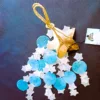 Sino de Vento|Coco e Capiz: Estrelas Brancas e Círculos Azuis – Harmonia e Brisa Celestial Leve a melodia suave do oceano e a luz das estrelas para o seu Lar! O Sino de Vento feito de Coco e Capiz (proveniente de conchas), com o seu design encantador de estrelas brancas e círculos azuis, é a peça de artesanato perfeita para quem procura equilibrar as energias do ambiente com beleza e serenidade. A Beleza das Conchas Capiz e do Elemento Ar As conchas de Capiz (também conhecidas como madrepérola translúcida) são famosas pela sua delicadeza e pelo som cristalino que produzem ao tocar umas nas outras. Combinadas com a base natural de casca de coco em forma de estrela, este mensageiro do vento une os elementos Terra e Ar: Som Terapêutico: O tilintar suave ajuda a relaxar a mente, sendo ideal para espaços de meditação, yoga, terapias energéticas e/ou varandas/terraços. Símbolo das Estrelas: No esoterismo, a estrela representa a guia espiritual, a esperança e a luz na escuridão. As cores azul e branco evocam a paz, a pureza e a proteção do céu. Cura pelo Feng Shui: Os sinos de vento são ferramentas essenciais no Feng Shui para dissipar energias estagnadas (Chi negativo) e atrair fluxo vital positivo para a entrada do seu Lar. Artesanato Sustentável e Decorativo Cada peça é única, criada por artesãos na Indonésia, feita de casca do coco em forma de estrela de 5 pontas e a textura orgânica das conchas. Este não é apenas uma peça decorativa, é um artigo de artesanato que respeita a natureza: Decoração Versátil: Fica perfeito tanto em interiores (perto de janelas) como em áreas exteriores cobertas, criando um ponto focal de luz, som e cor. Cromoterapia: O azul suave promove a comunicação e a calma, enquanto o branco limpa a vibração do espaço. Presente com Intenção: Um presente maravilhoso para quem se mudou para uma casa nova ou precisa de um toque de tranquilidade no seu dia a dia. Especificações do Produto Materiais: Casca de coco natural e conchas Capiz genuínas. Design: Estrelas em tons de Azul e Branco. Uso: Interior e Exterior (protegido da chuva direta). Vibração: Paz, Guia Espiritual e Fluidez. ✨ Deixe a Energia Fluir no Seu Lar Preencha o seu lar com a melodia das estrelas e a proteção do mar. O Sino de Vento de Coco e Capiz é "aquele" toque especial que o seu lar merece. Dica Ativadora: Pendure o seu sino de vento perto de uma janela, ou da porta da sua varanda ou quintal para filtrar as energias que entram para dentro do seu Lar! Comprar Sino de Vento Estrelas – Traga a Harmonia para Casa