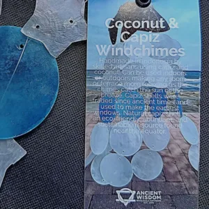 Sino de Vento|Coco e Capiz: Estrelas Brancas e Círculos Azuis – Harmonia e Brisa Celestial Leve a melodia suave do oceano e a luz das estrelas para o seu Lar! O Sino de Vento feito de Coco e Capiz (proveniente de conchas), com o seu design encantador de estrelas brancas e círculos azuis, é a peça de artesanato perfeita para quem procura equilibrar as energias do ambiente com beleza e serenidade. A Beleza das Conchas Capiz e do Elemento Ar As conchas de Capiz (também conhecidas como madrepérola translúcida) são famosas pela sua delicadeza e pelo som cristalino que produzem ao tocar umas nas outras. Combinadas com a base natural de casca de coco em forma de estrela, este mensageiro do vento une os elementos Terra e Ar: Som Terapêutico: O tilintar suave ajuda a relaxar a mente, sendo ideal para espaços de meditação, yoga, terapias energéticas e/ou varandas/terraços. Símbolo das Estrelas: No esoterismo, a estrela representa a guia espiritual, a esperança e a luz na escuridão. As cores azul e branco evocam a paz, a pureza e a proteção do céu. Cura pelo Feng Shui: Os sinos de vento são ferramentas essenciais no Feng Shui para dissipar energias estagnadas (Chi negativo) e atrair fluxo vital positivo para a entrada do seu Lar. Artesanato Sustentável e Decorativo Cada peça é única, criada por artesãos na Indonésia, feita de casca do coco em forma de estrela de 5 pontas e a textura orgânica das conchas. Este não é apenas uma peça decorativa, é um artigo de artesanato que respeita a natureza: Decoração Versátil: Fica perfeito tanto em interiores (perto de janelas) como em áreas exteriores cobertas, criando um ponto focal de luz, som e cor. Cromoterapia: O azul suave promove a comunicação e a calma, enquanto o branco limpa a vibração do espaço. Presente com Intenção: Um presente maravilhoso para quem se mudou para uma casa nova ou precisa de um toque de tranquilidade no seu dia a dia. Especificações do Produto Materiais: Casca de coco natural e conchas Capiz genuínas. Design: Estrelas em tons de Azul e Branco. Uso: Interior e Exterior (protegido da chuva direta). Vibração: Paz, Guia Espiritual e Fluidez. ✨ Deixe a Energia Fluir no Seu Lar Preencha o seu lar com a melodia das estrelas e a proteção do mar. O Sino de Vento de Coco e Capiz é "aquele" toque especial que o seu lar merece. Dica Ativadora: Pendure o seu sino de vento perto de uma janela, ou da porta da sua varanda ou quintal para filtrar as energias que entram para dentro do seu Lar! Comprar Sino de Vento Estrelas – Traga a Harmonia para Casa